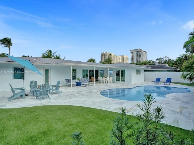 rear view of house featuring a patio area, fence, a fenced in pool, and a yard