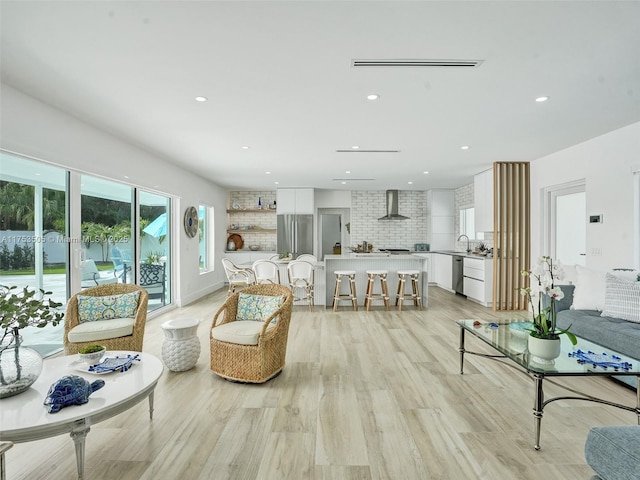 living room with light wood finished floors, visible vents, and recessed lighting