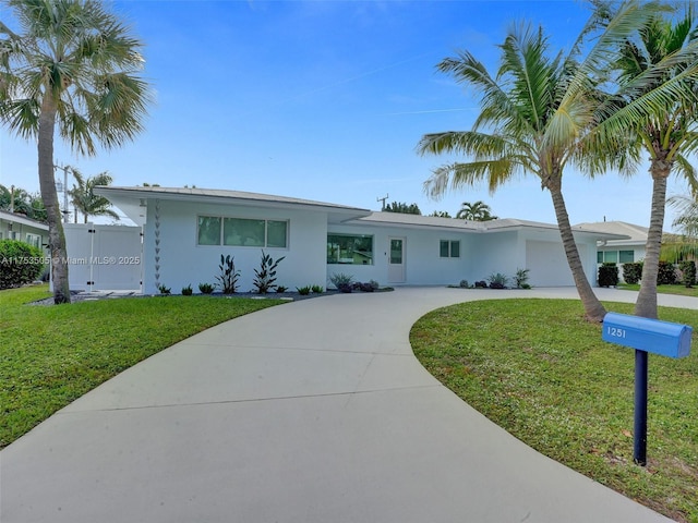 ranch-style home featuring concrete driveway, a front lawn, an attached garage, and stucco siding