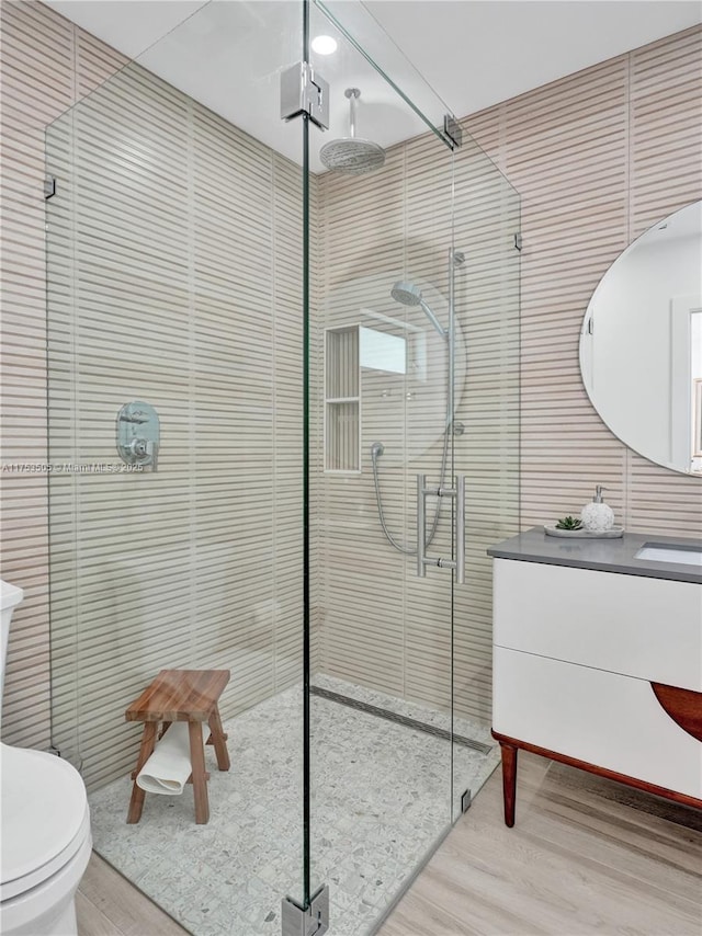 bathroom with toilet, a stall shower, wood finished floors, and vanity