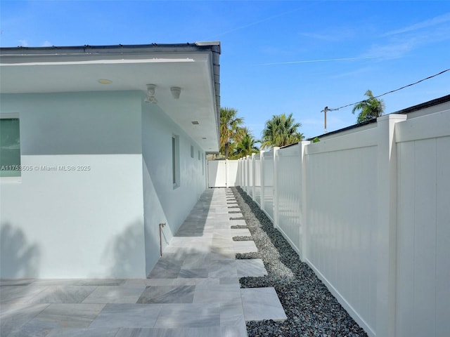 view of side of home with fence and stucco siding