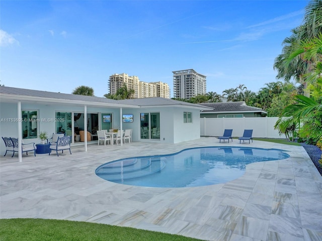 rear view of property featuring stucco siding, fence, a fenced in pool, and a patio