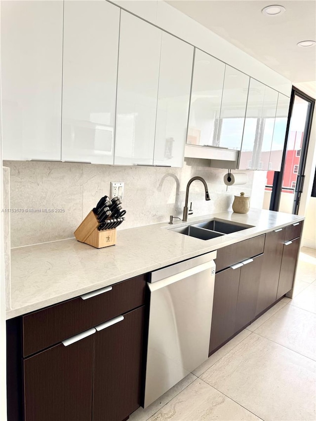 kitchen with tasteful backsplash, stainless steel dishwasher, dark brown cabinets, a sink, and modern cabinets