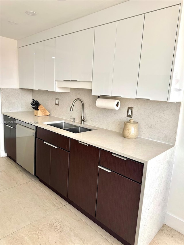 kitchen featuring white cabinetry, stainless steel dishwasher, light countertops, and a sink