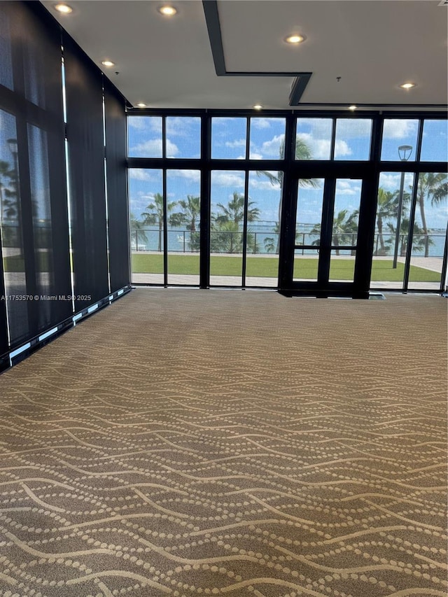 carpeted spare room featuring recessed lighting and a wall of windows