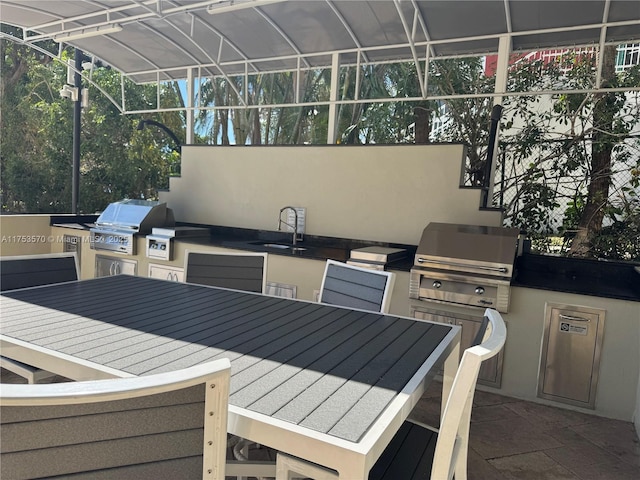 view of patio / terrace with a sink, outdoor dining space, area for grilling, and a grill
