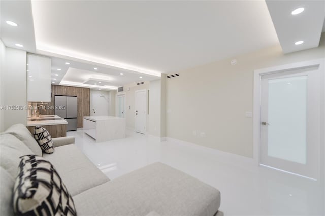 living room featuring a raised ceiling and recessed lighting