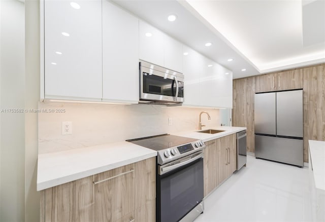 kitchen with stainless steel appliances, modern cabinets, a sink, and decorative backsplash