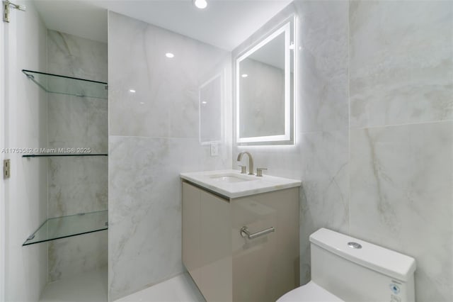 bathroom with toilet, tile walls, and vanity