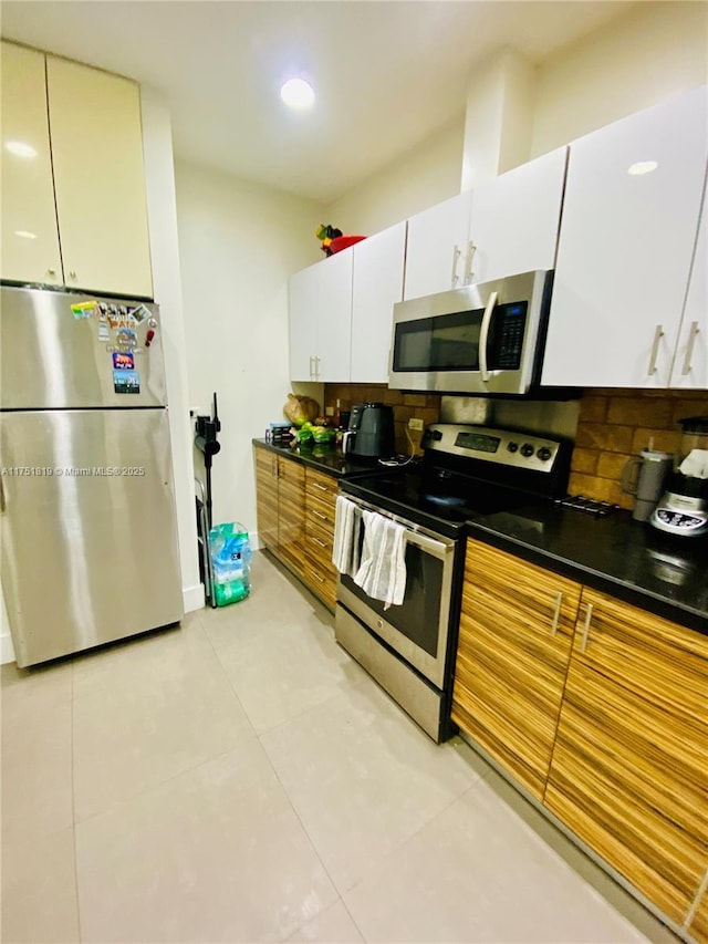 200 Azure Way, Miami Springs, FL 33166 - kitchen featuring light tile patterned floors, white cabinets, appliances with stainless steel finishes, tasteful backsplash, and dark countertops