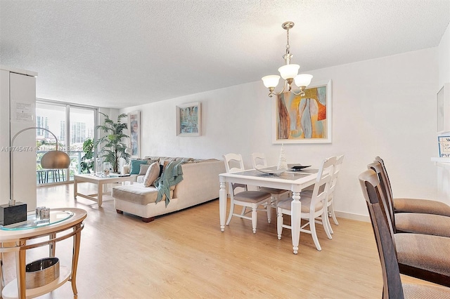 dining area featuring expansive windows, a notable chandelier, light wood-style flooring, and a textured ceiling