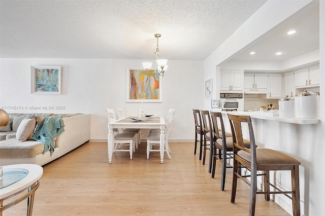 dining room with baseboards, a textured ceiling, light wood-style floors, a chandelier, and recessed lighting