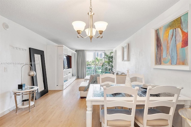 dining room with light wood-type flooring, a notable chandelier, and a textured ceiling