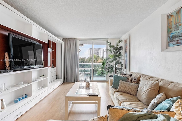 living room featuring a textured ceiling, a textured wall, and light wood-style flooring