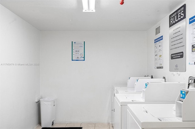 community laundry room featuring visible vents, light tile patterned flooring, and independent washer and dryer