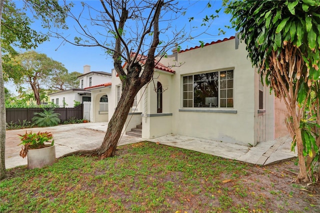 back of property with a tiled roof, fence, a patio, and stucco siding