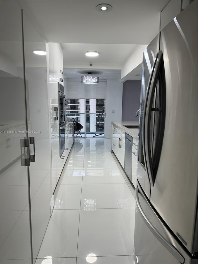 kitchen with stainless steel appliances, light countertops, a sink, and white cabinetry