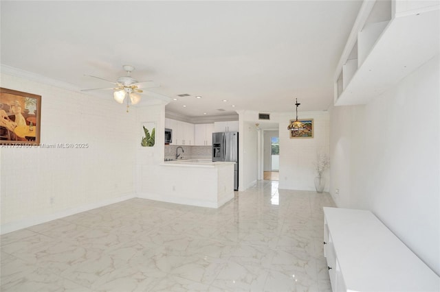 unfurnished living room featuring a sink, marble finish floor, and crown molding