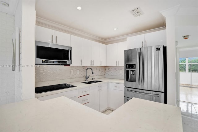 kitchen with a sink, visible vents, white cabinets, ornamental molding, and appliances with stainless steel finishes