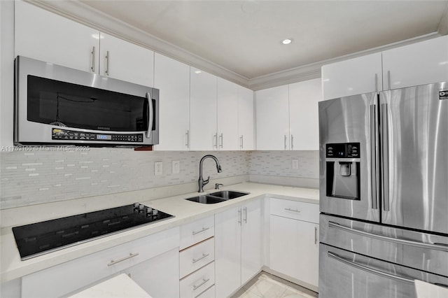 kitchen featuring crown molding, decorative backsplash, appliances with stainless steel finishes, white cabinets, and a sink