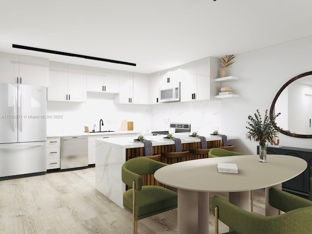 kitchen featuring white appliances, white cabinetry, light wood-type flooring, and a sink