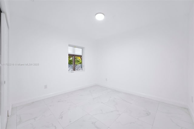 empty room featuring marble finish floor and baseboards