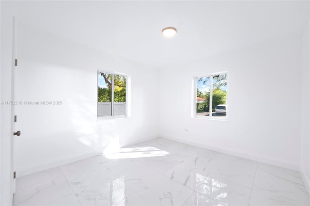 spare room featuring marble finish floor and baseboards