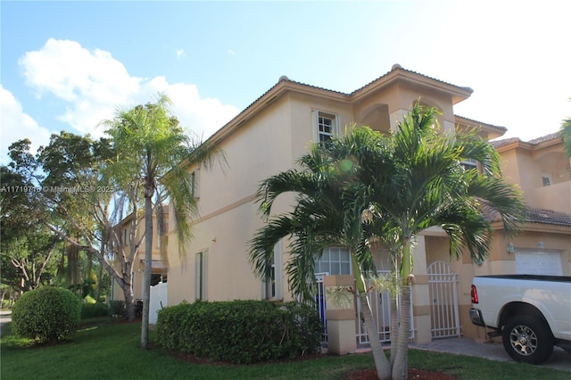 view of front of house with a front yard, a tiled roof, and stucco siding