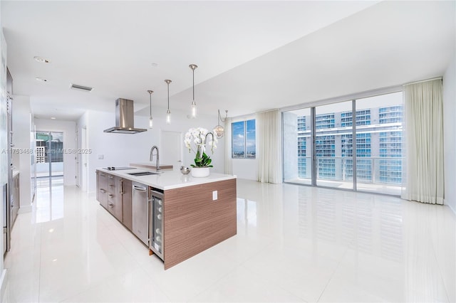 kitchen featuring an island with sink, modern cabinets, ventilation hood, light countertops, and a sink