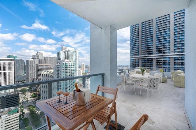 balcony with outdoor dining space and a city view