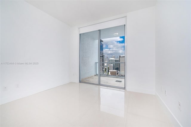 empty room with tile patterned flooring, baseboards, and a wall of windows