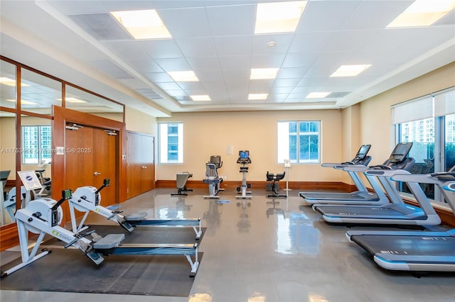 workout area with a paneled ceiling and baseboards