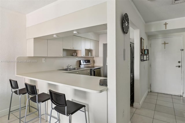 8425 NW 8th St Unit 404, Miami, FL 33126 - kitchen with stainless steel electric range, a kitchen bar, light countertops, light tile patterned floors, and open shelves