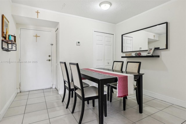 dining area with ornamental molding, light tile patterned flooring, a textured ceiling, and baseboards