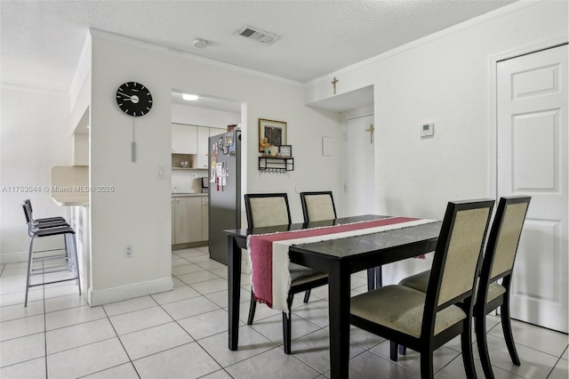 dining space with light tile patterned floors, a textured ceiling, visible vents, baseboards, and ornamental molding