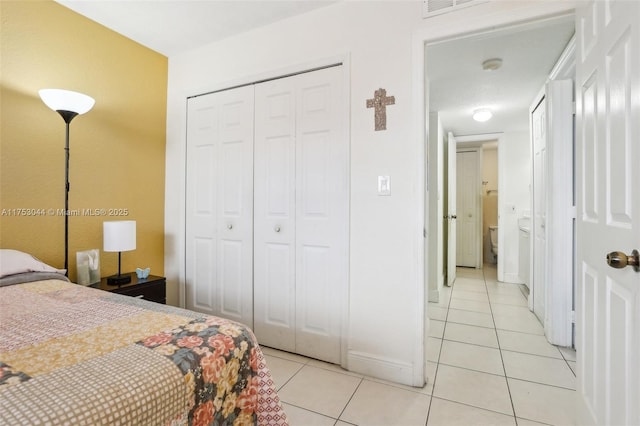 bedroom featuring light tile patterned floors, baseboards, and a closet