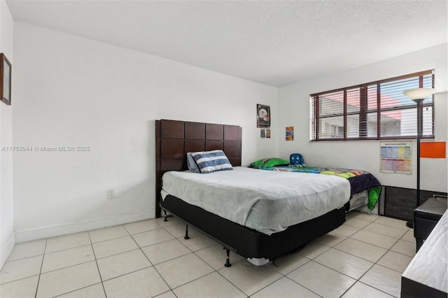 bedroom featuring light tile patterned floors, baseboards, and a textured ceiling