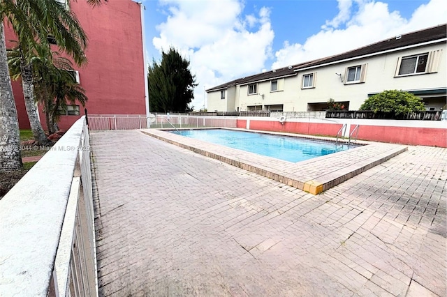 community pool with a patio area and fence