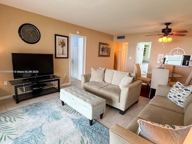 living room featuring light tile patterned floors, ceiling fan, visible vents, and baseboards