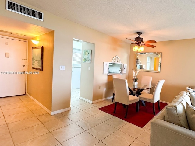 unfurnished dining area featuring visible vents, a ceiling fan, light tile patterned flooring, a textured ceiling, and baseboards