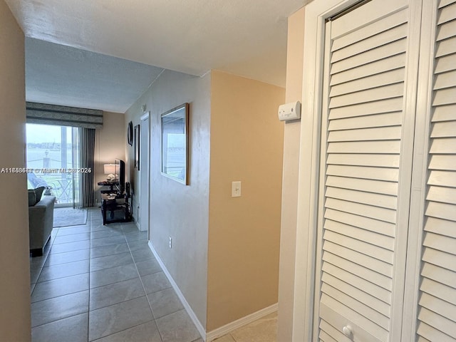 hallway with tile patterned flooring, a textured ceiling, and baseboards