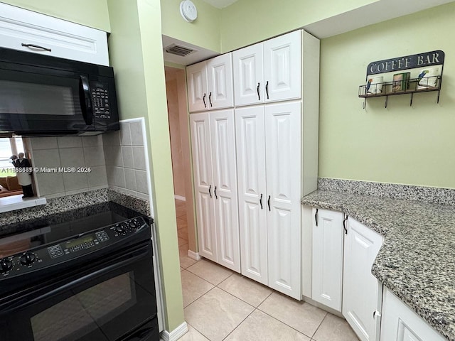 kitchen with light tile patterned floors, visible vents, light stone counters, black appliances, and white cabinetry