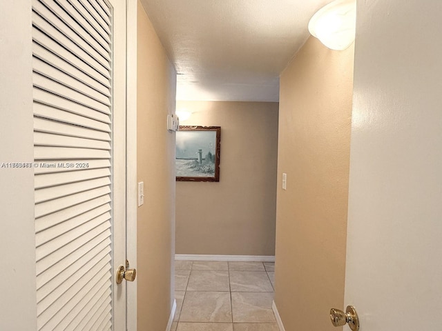 hallway featuring light tile patterned floors and baseboards