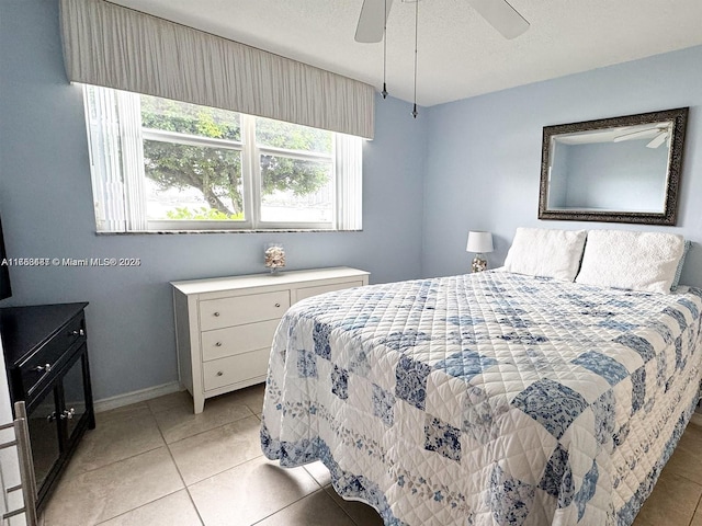 bedroom with ceiling fan, a textured ceiling, baseboards, and light tile patterned floors