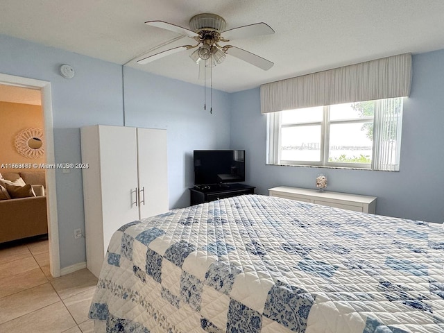 bedroom with light tile patterned floors, ceiling fan, and a textured ceiling