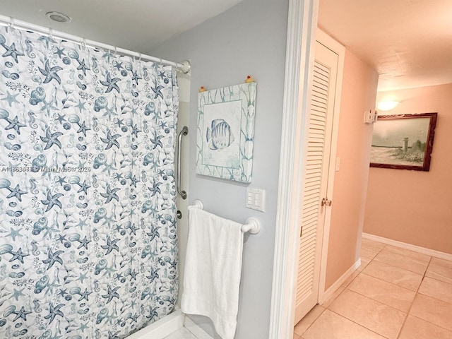 bathroom featuring a closet, baseboards, a shower with shower curtain, and tile patterned floors