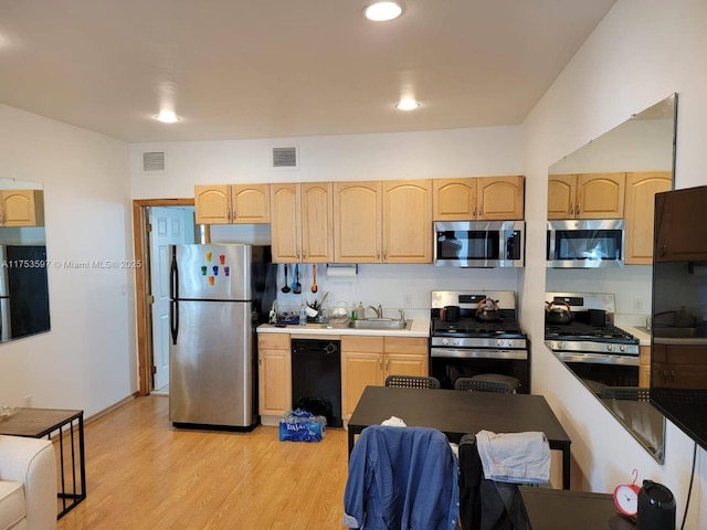 kitchen with light brown cabinets, visible vents, and black appliances