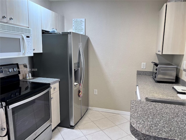 kitchen with light tile patterned floors, a toaster, baseboards, and stainless steel appliances