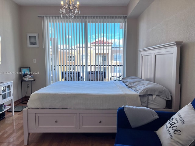 bedroom featuring access to exterior, a chandelier, and wood finished floors