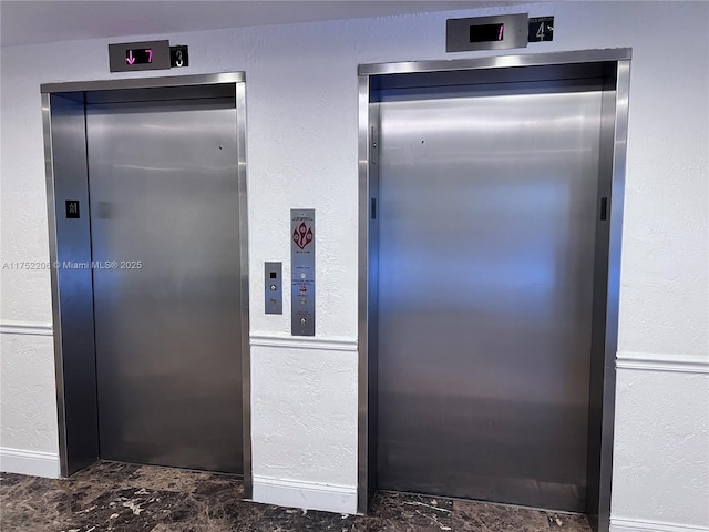 details featuring elevator, baseboards, and a textured wall